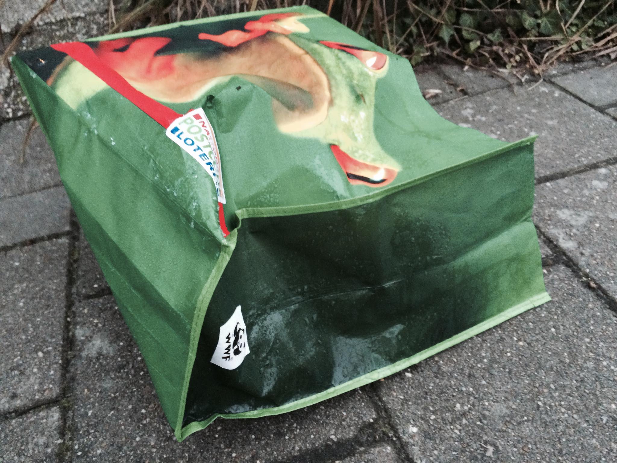 Voor 'het milieu' sponsort de Postcode Loterij een groene tas zwerfvuil met kikkerplaatje en WWF-logo