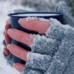 Woman,Holding,A,Mug,In,Her,Hands.,The,Gloves,Are